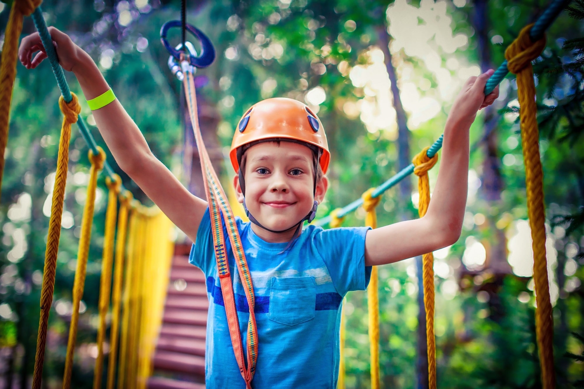 Little boy standing on a ropes-course bridge