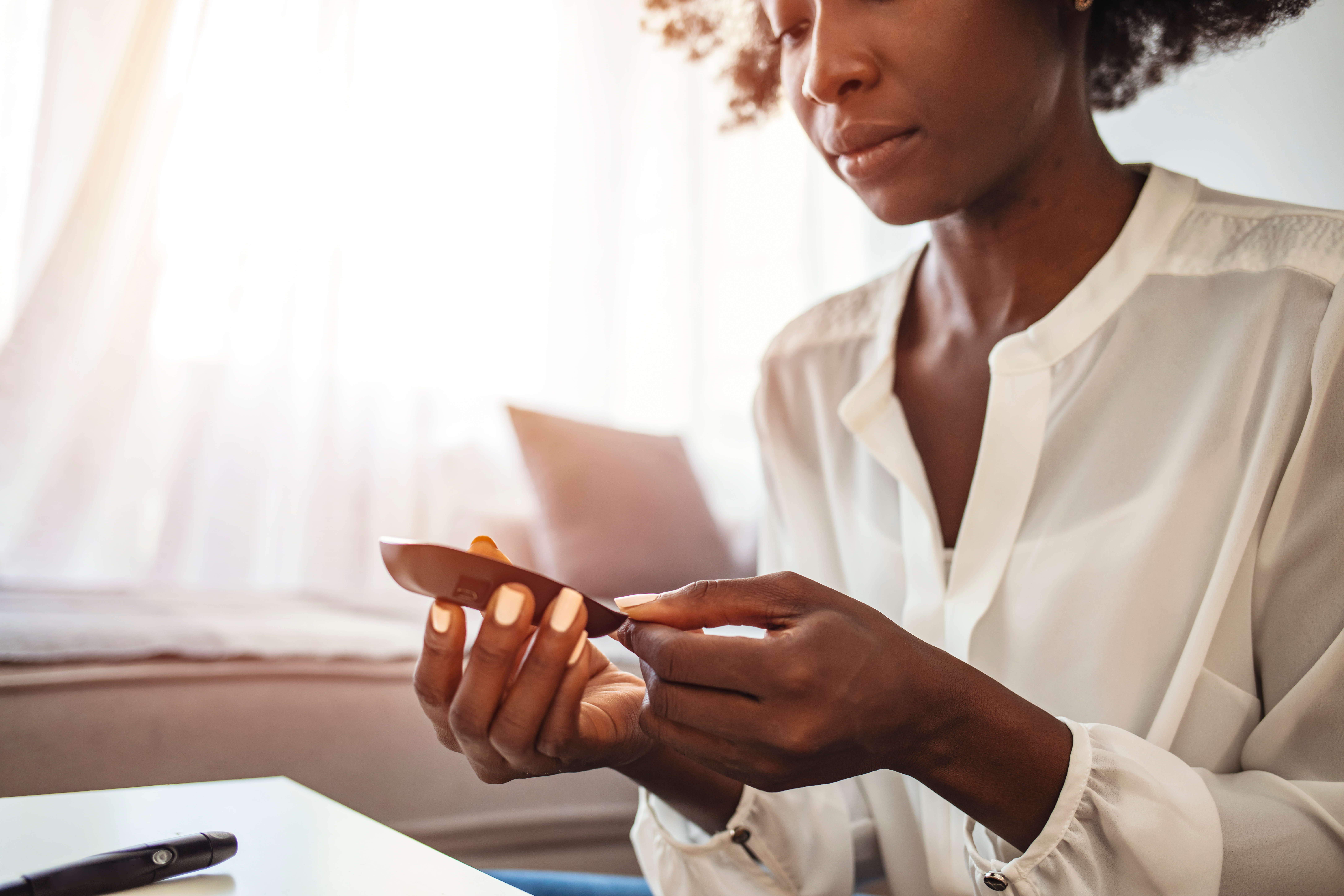 A woman checks her blood sugar using a glucose meter at home