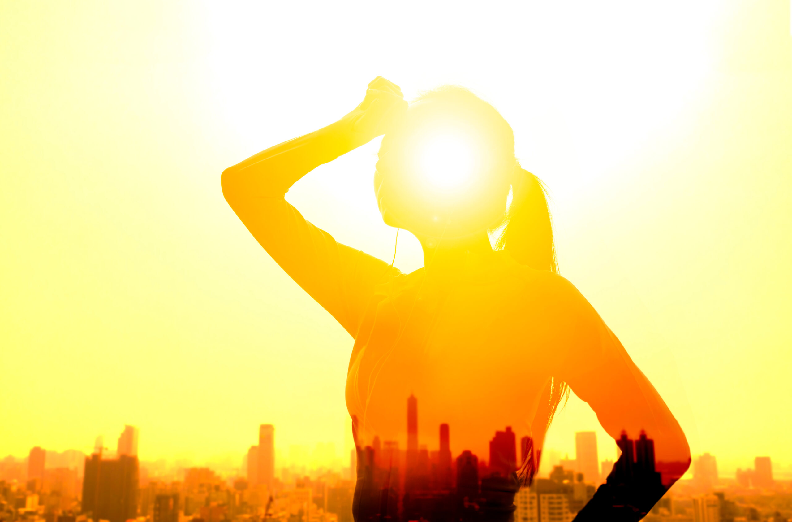 Silhouette of a woman wiping sweat from her forehead under intense summer sunlight