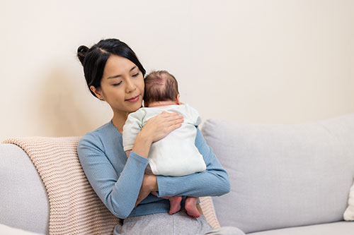 A mother tapping her newborn for hiccups